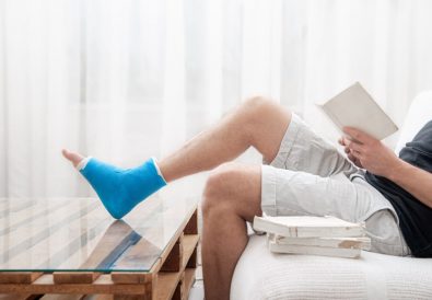 man-with-broken-leg-cast-reads-books-against-light-background-interior-room
