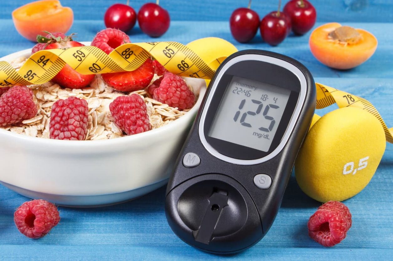 Glucometer with result of sugar level, oat flakes with fruits, tape measure and dumbbells for fitness, concept of diabetes, diet, slimming and healthy lifestyles